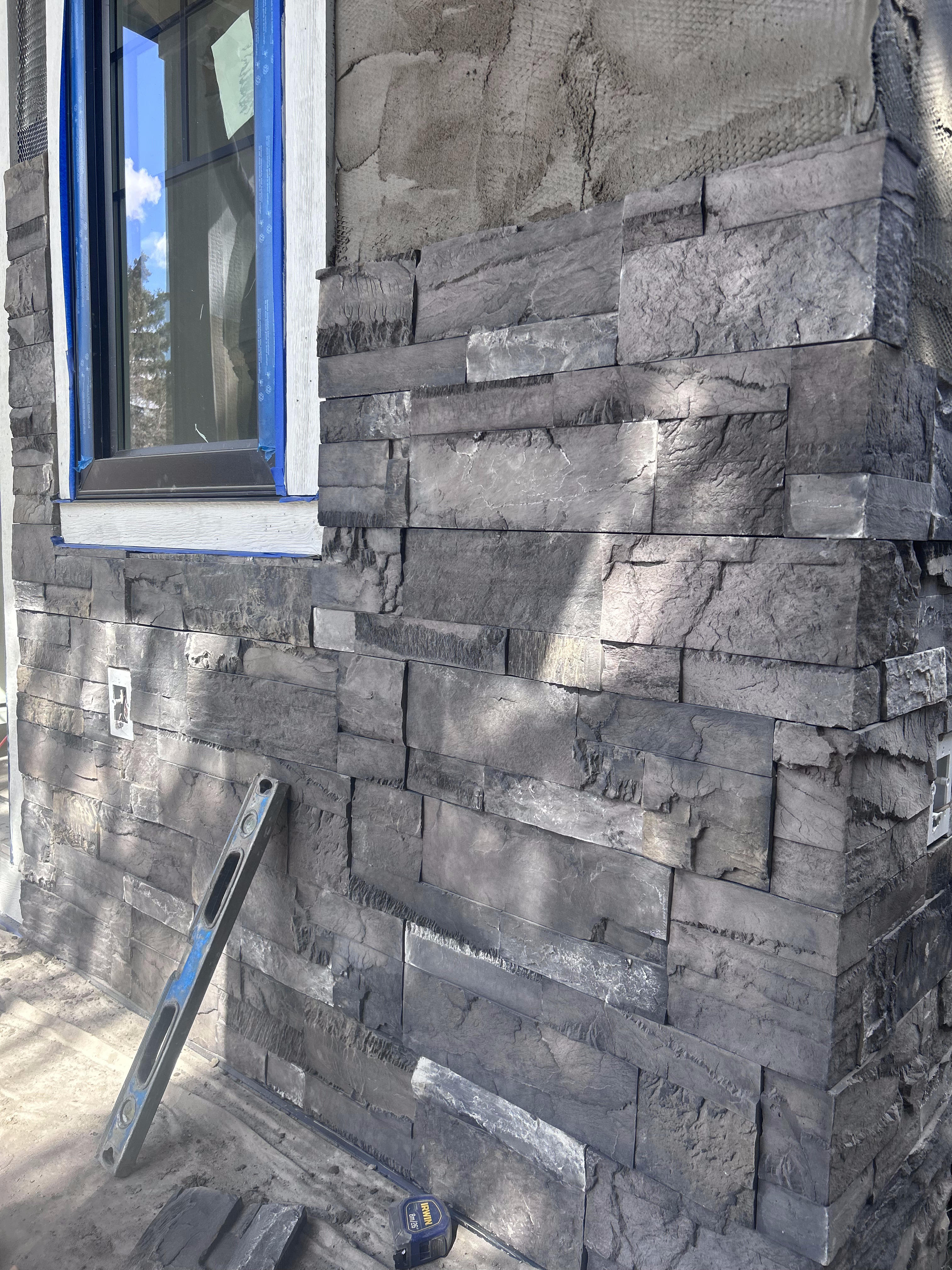 Gray stacked stone veneer installed around a window opening